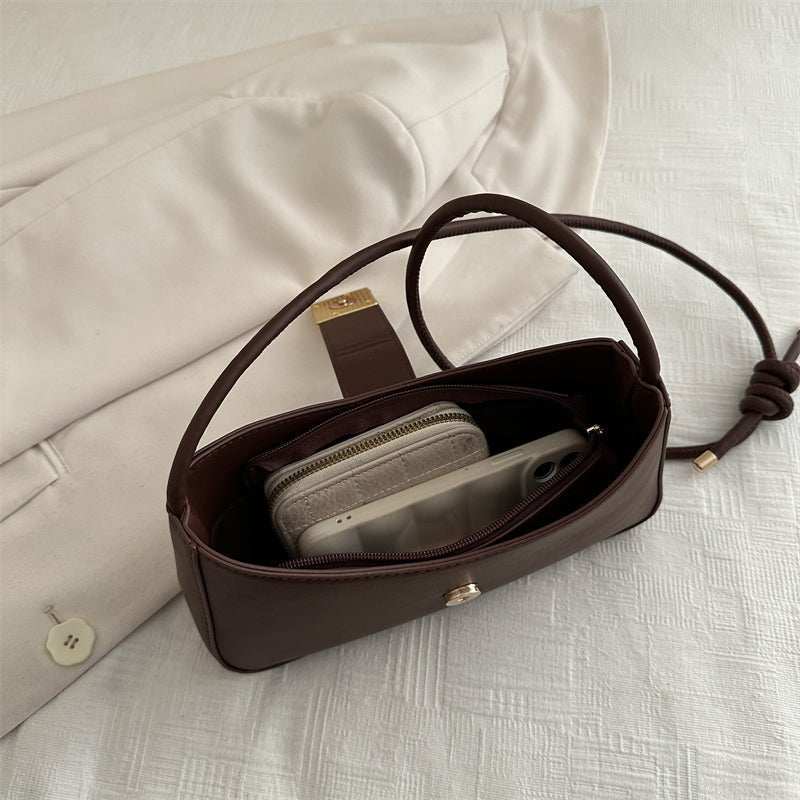 Women’s everyday structured handbag displayed with essentials—phone, wallet, keys—to show storage capacity