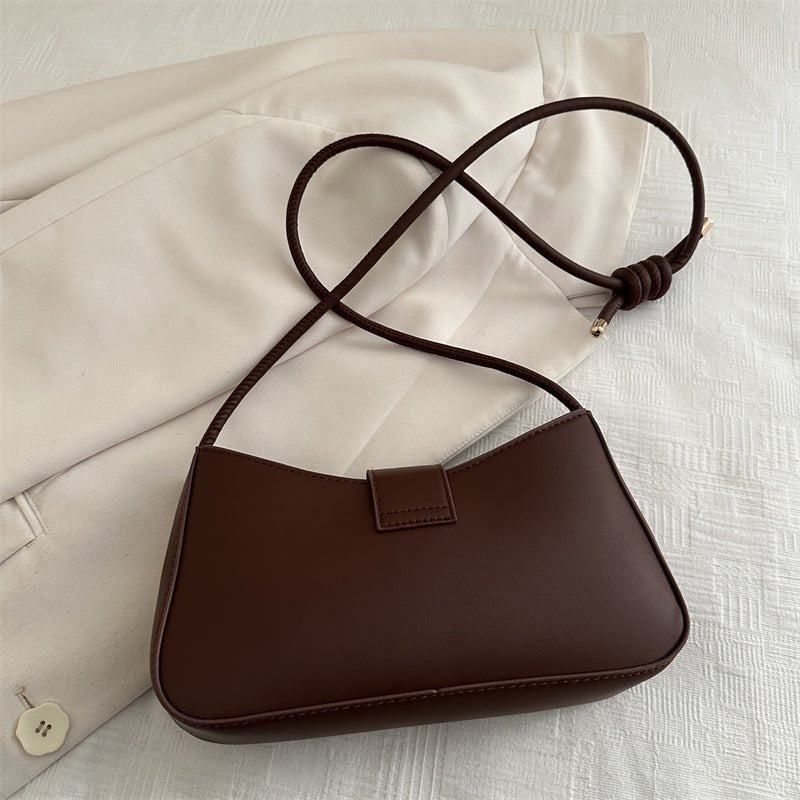 Elegant black handbag for women with gold zipper hardware and adjustable crossbody strap, on white background