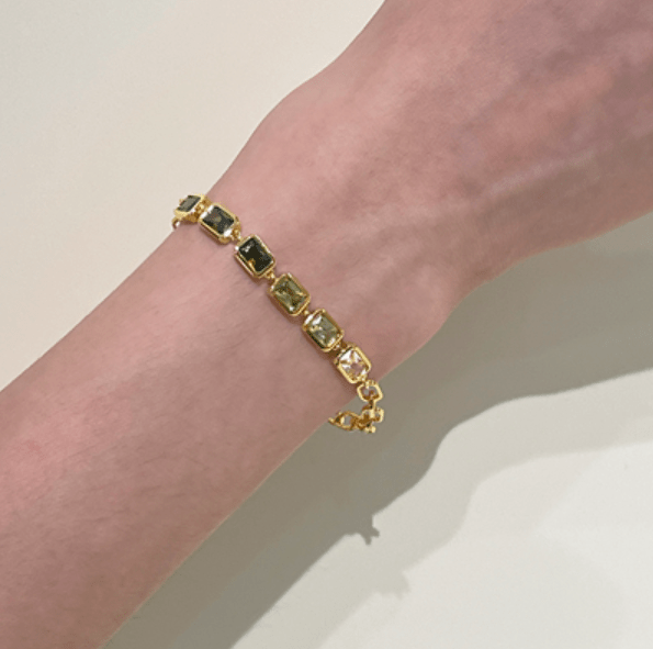 Vintage gold bracelet with green zircon gemstones displayed on wrist, highlighting elegant design and superior craftsmanship.