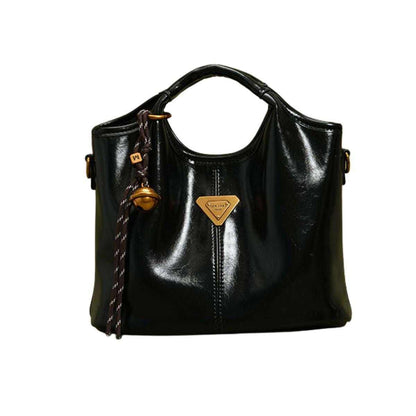 Elegant PU Leather Women’s Tote in glossy black with vintage gold-tone emblem and decorative tassel pendant